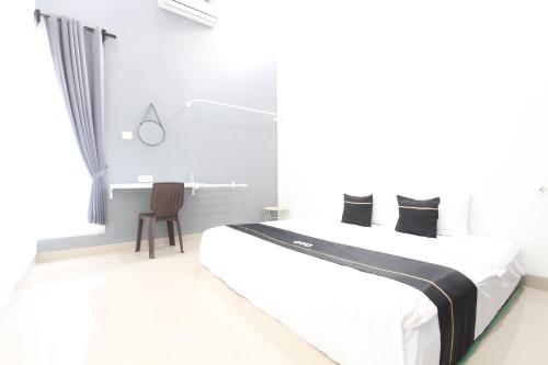 a white bedroom with a bed and a desk at Capital O 93939 Oikodomeo in Salatiga