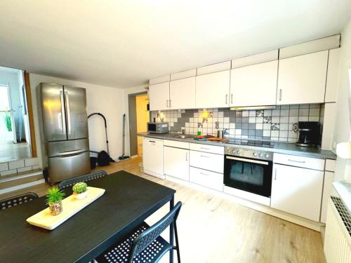 a large kitchen with white cabinets and a black table at Beautiful Apartments in Zülpich in Zülpich