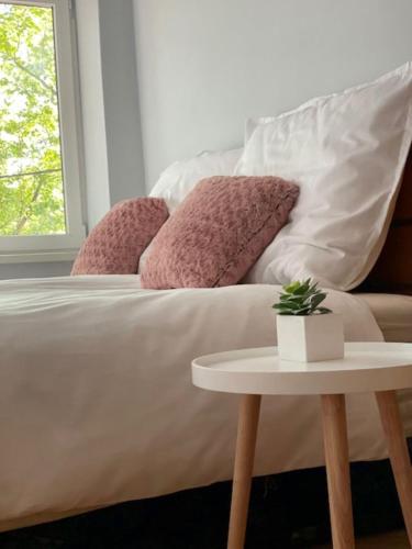 a white bed with pink pillows and a table at LaBONI Apartman in Miskolctapolca