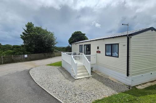 a small white building with a staircase next to a road at 2 bed 2 ensuite Holiday Home in St Austell