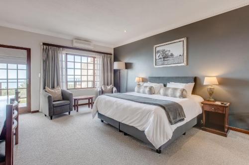 a bedroom with a large bed and a chair at Garden Route Ilita Lodge in Groot Brak Rivier