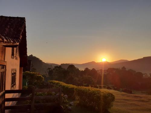 a sunset in the mountains with a house in the foreground at Pousada Pé da Mata in Aiuruoca