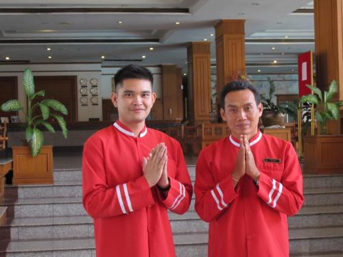 two men in red robes praying in a building at Rimpao Hotel in Kalasin