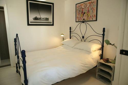 ein Schlafzimmer mit einem weißen Bett mit einem schwarzen Rahmen in der Unterkunft The Salty Mermaid Fisherman's Cottage, Whitstable in Kent