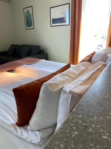 een wit bed met bruine en witte kussens erop bij Marstrands Havshotell in Marstrand