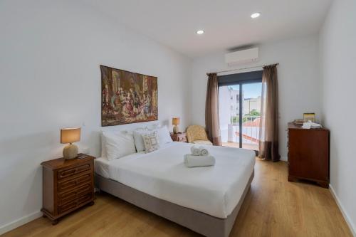 a bedroom with a large white bed and a window at Ginjinha in Setúbal
