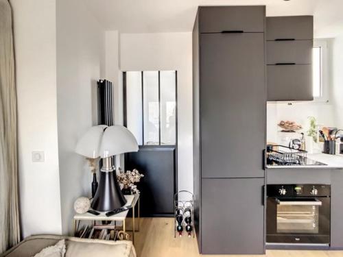 une cuisine blanche avec une table et une lampe dedans dans l'établissement Appartement Design proche Tour Eiffel avec Balcon, à Paris