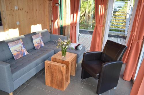 a living room with a blue couch and two chairs at Tolles Ferienhaus mit Sauna und Whirlpool in Wolfsberg