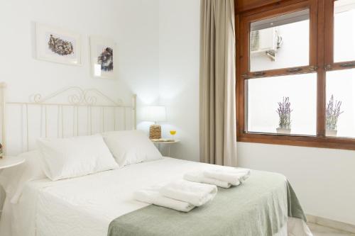 a bedroom with a bed with white sheets and a window at Apartamento independiente en Playa de Regla. in Chipiona