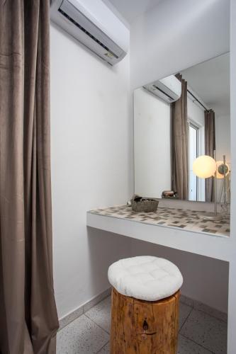 a bathroom with a mirror and a wooden stool at Lisabeth Apartments in Faliraki
