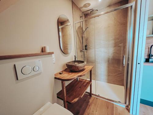 La salle de bains est pourvue d'une douche et d'un bol sur une table. dans l'établissement Domaine du Mimosa, à Perros-Guirec