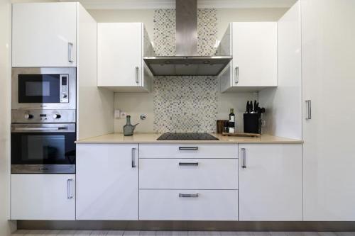 a white kitchen with white cabinets and appliances at Close to Everything Bright Modern Apartment in Nazaré