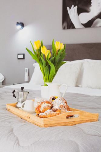 een dienblad met gebak en bloemen op een bed bij B&B Peonies in Castellammare di Stabia