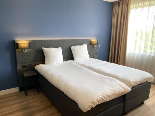 a bedroom with a large bed with white sheets and pillows at OZO Hotels Antares Airport in Hoofddorp
