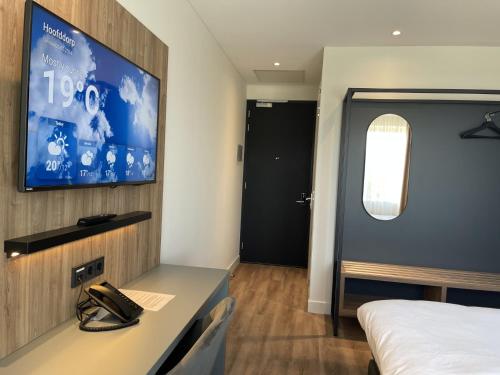 a room with a bed and a tv on a wall at OZO Hotels Antares Airport in Hoofddorp