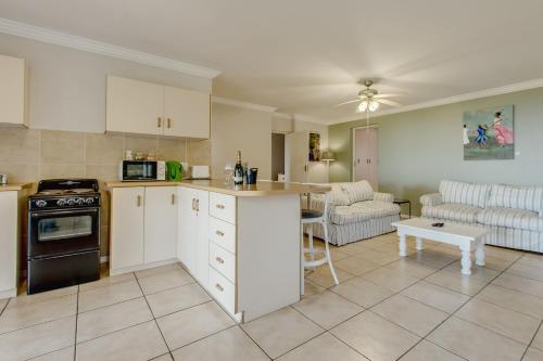a kitchen with white cabinets and a living room at Garden Route Ilita Lodge in Groot Brak Rivier
