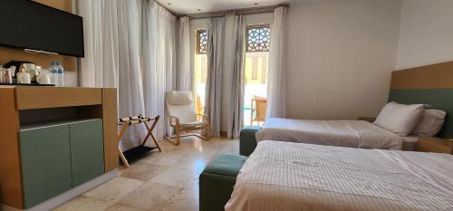 a hotel room with two beds and a television at Nayah Boutique Stays in Hurghada