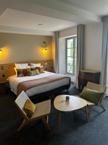 une chambre d'hôtel avec un grand lit et une table dans l'établissement Domaine de l'Ecorcerie, à Poitiers