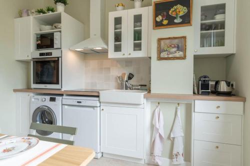 une cuisine avec des armoires blanches et une laveuse et une sécheuse dans l'établissement Luxe et déco anglaise Tours centre Loire Valley, à Tours