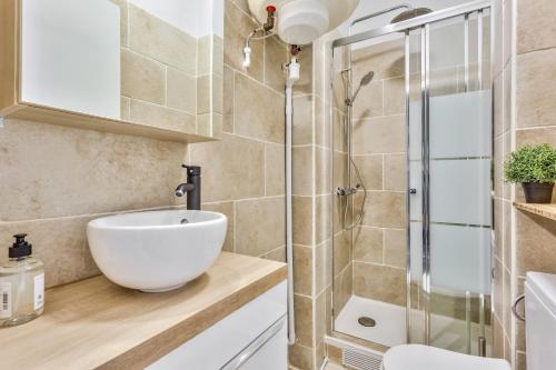 La salle de bains est pourvue d'un lavabo blanc et d'une douche. dans l'établissement Studio Cozy avec vue sur la tour Eiffel, à Clichy