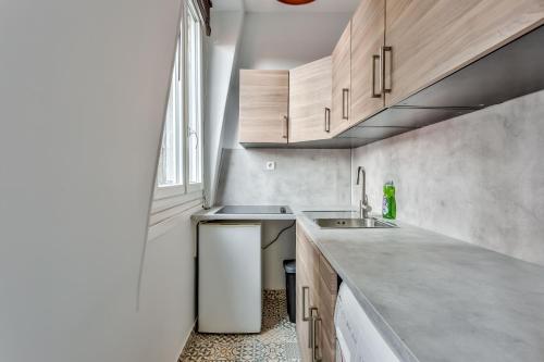 Elle comprend une petite cuisine avec des placards en bois et un évier. dans l'établissement Studio Cozy avec vue sur la tour Eiffel, à Clichy