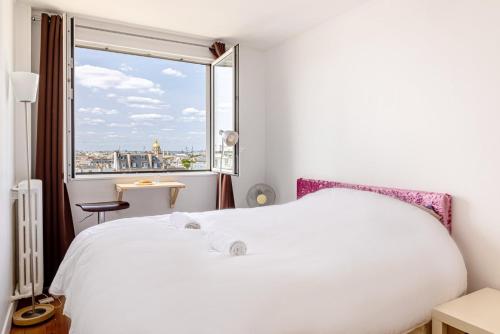 un lit blanc dans une chambre avec une fenêtre dans l'établissement GuestReady - Magic View Montparnasse Big Terrace, à Paris
