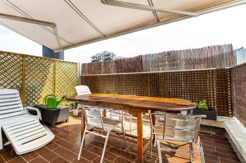 eine Außenterrasse mit einem Holztisch und Stühlen in der Unterkunft GuestReady - Magic View Montparnasse Big Terrace in Paris