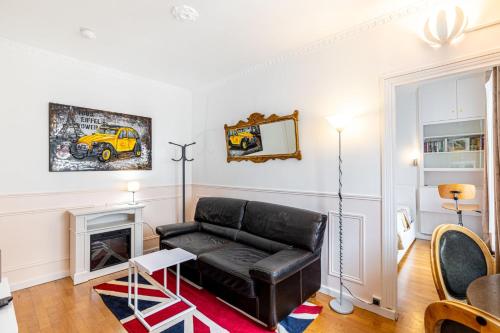 un salon avec un canapé en cuir noir et une cheminée dans l'établissement GuestReady - Appartement baigné de lumière au 7e., à Paris
