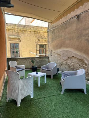 a patio with chairs and tables and a wall at Doctor House standard, suites & luxury rooms in Enna