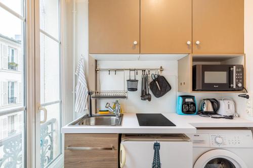 une petite cuisine avec un évier et un micro-ondes dans l'établissement GuestReady - Appartement baigné de lumière au 7e., à Paris