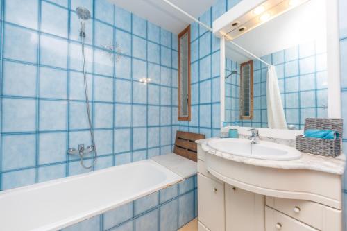 a blue tiled bathroom with a sink and a bathtub at Boreal in Alcudia