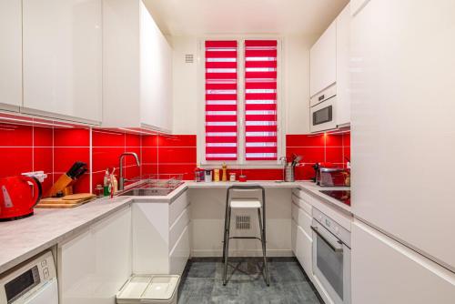- une cuisine rouge et blanche avec des placards blancs et un tabouret dans l'établissement GuestReady - Boulogne near Roland-Garros, à Boulogne-Billancourt