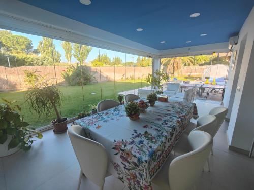 uma sala de jantar com uma mesa longa e cadeiras brancas em Casa de sol, piscina y jacuzzi con 4 hab en Comunidad de Madrid em Algete