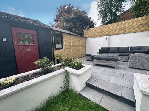 a patio with a couch and a red door at Garden Lodge in Belfast