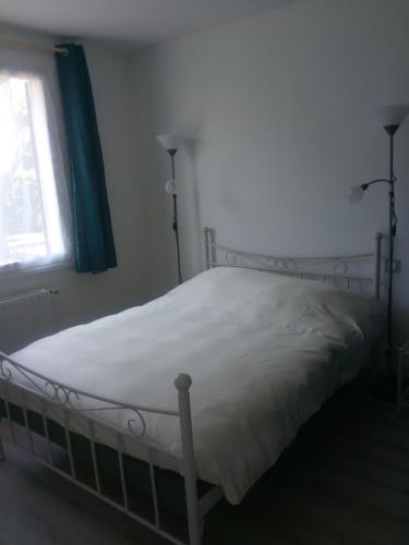 - un lit blanc dans une chambre avec fenêtre dans l'établissement maison pour vacances en famille, à Biscarrosse