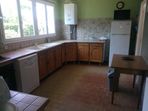 une cuisine avec des armoires en bois et un réfrigérateur blanc dans l'établissement maison pour vacances en famille, à Biscarrosse