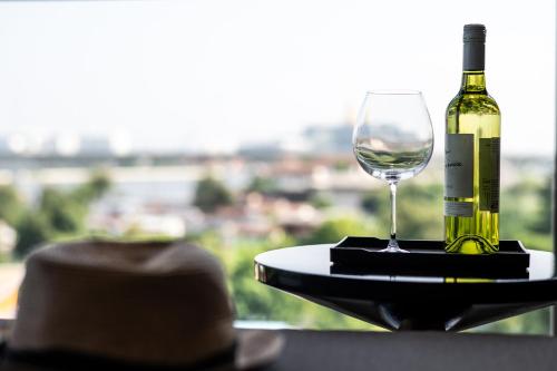 a bottle of wine and a wine glass on a table at WE HOTEL RIVERFRONT in Bang Su
