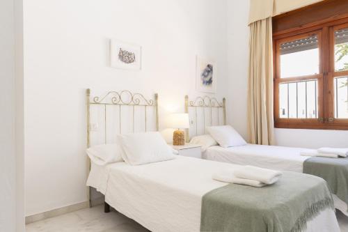 two beds in a room with white walls at Apartamento Playa de Regla con terraza 1 in Chipiona