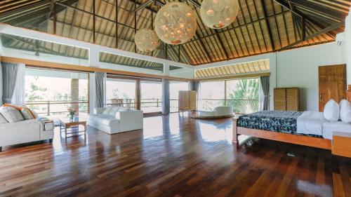 a bedroom with a bed and a living room at Villa Tamaro Bali in Ubud