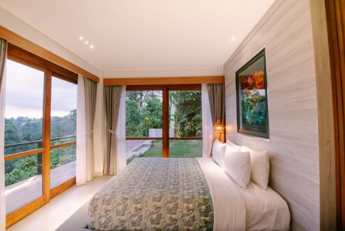 a bedroom with a bed and large windows at Villa Tamaro Bali in Ubud
