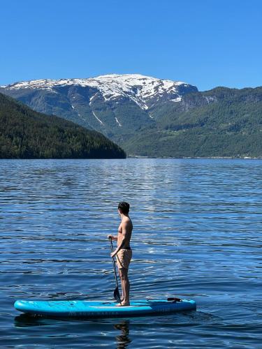 a man standing on a paddle board in the water at Studio apartment in Sogndal