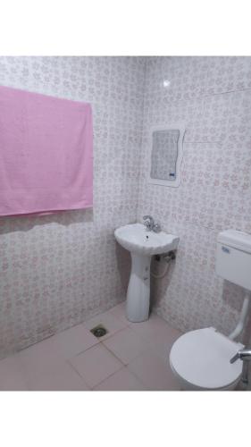a bathroom with a white toilet and a sink at Serene Stay Villa by Doctors in Gulmarg