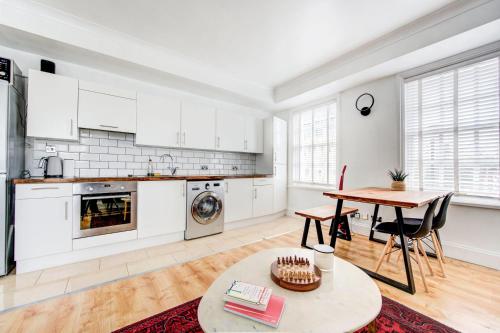 eine Küche mit weißen Schränken und einem Tisch im Zimmer in der Unterkunft GuestReady - Estadia de charme em Limehouse in London