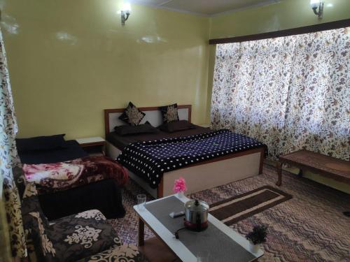 a bedroom with two beds and a couch and a table at Serene Stay Villa by Doctors in Gulmarg