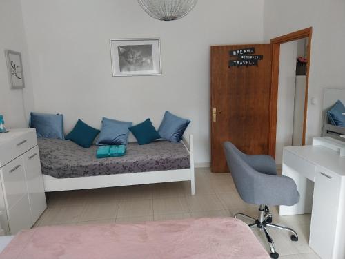 a bedroom with a bed with blue pillows and a chair at Santa Lucia in Vetovo
