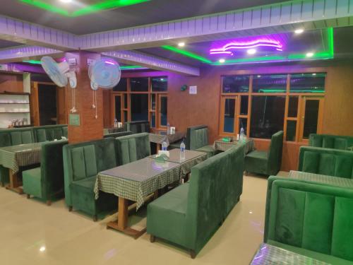 a restaurant with green chairs and tables and lights at Serene Stay Villa by Doctors in Gulmarg