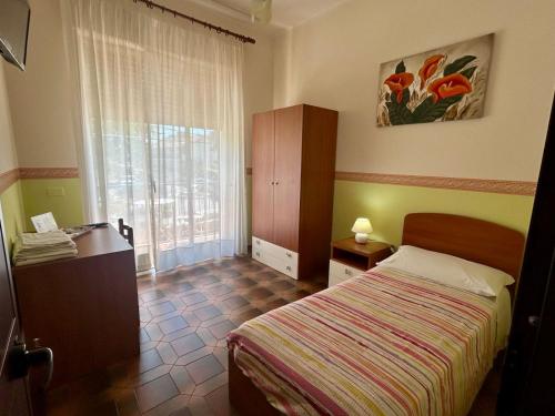 sypialnia z łóżkiem, komodą i oknem w obiekcie Albergo Mendolia w mieście Milazzo