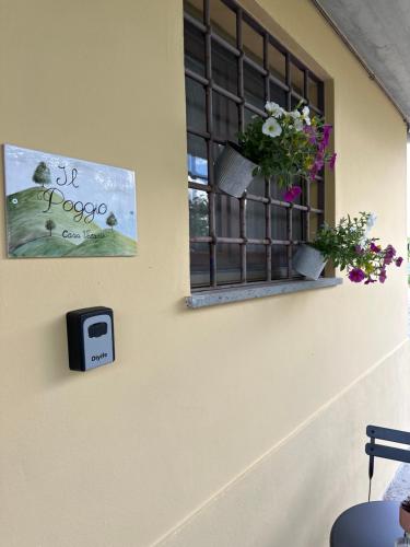 a window with flowers and a clock on a wall at Casa vacanze Il Poggio in Fabro