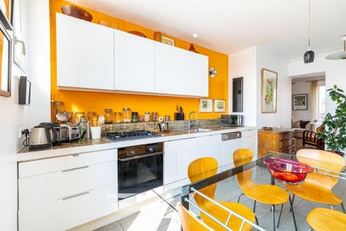 une cuisine avec des armoires blanches et une table en verre dans l'établissement GuestReady - Appartement Parisien dans le 10ème, à Paris