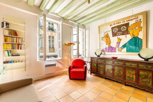 un salon avec une chaise rouge et un grand tableau dans l'établissement GuestReady - Parisian bliss near the Louvre Museum, à Paris
